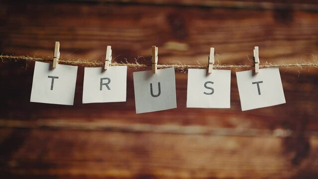 The word trust. Letters on cards on wooden background. Concept of confidence or faith and lettering or phrase.