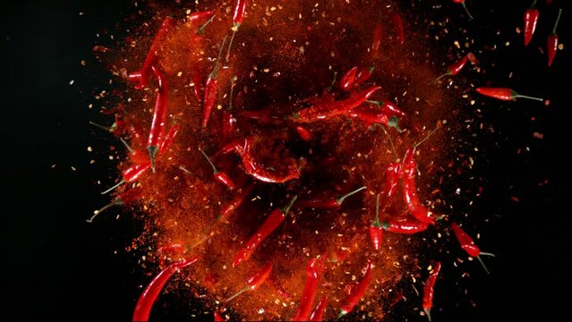 Super slow motion of rotating chilli peppers isolated on black. Overhead view, filmed on high speed cinema camera, 1000 fps. Ultimate perspective and concept of flying food.