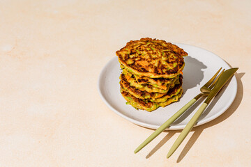 A stack of fried vegetable pancakes, made from zucchini and carrot, shot with hard light with...