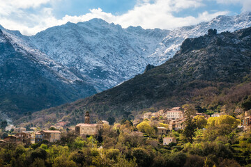 Fototapeta na wymiar The village of Feliceto in the Balagne region of Corsica with snow capped mountains in the distance