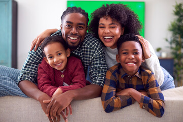 Portrait Of Family Sitting On Sofa Watching Movie On Green Screen TV At Home