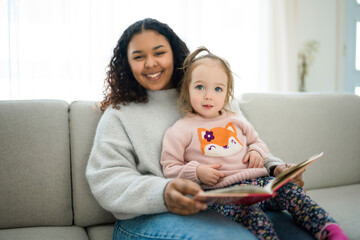 babysitter black woman read book with little child girl - obrazy, fototapety, plakaty