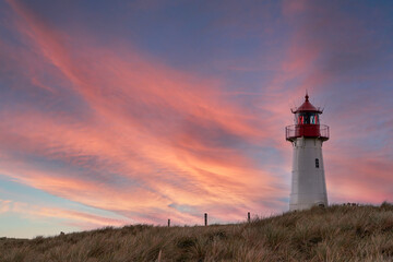 Fototapeta na wymiar Lighthouse List-West on the island Sylt at sunset. Dramatic sunset sky and lighthouse.
