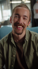 Obraz premium A young caucasian man is sitting on the chair in the university, smiling and looking at the camera