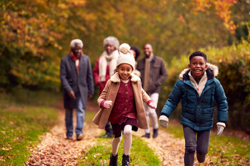 Smiling Multi-Generation Family Having Fun Walking Through Autumn Countryside Together