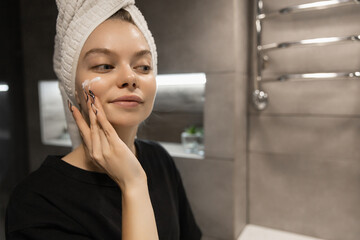 beautiful woman applying cream on her skin in the bathroom before going to bed