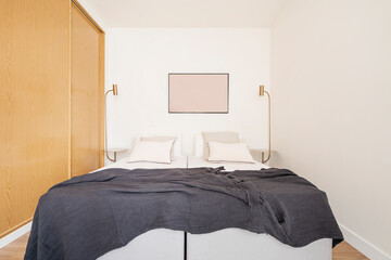 bedroom with a large split bed, built-in wardrobe with sliding wooden doors, side tables with matching lamps and blue blankets