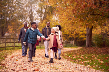 Smiling Multi-Generation Family Having Fun Walking Through Autumn Countryside Together