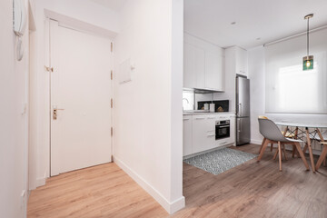 Entrance hall of a house with access to a kitchen with a circular dining table and chairs in a vacation rental apartment