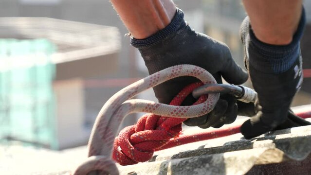 Worker hands securing life rope in a construction site roof closing a carabiner