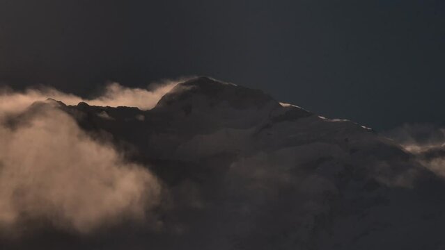 Beautiful scenery of snow caped mountain with clouds moving near by. Mountain peak with during sunset on top, Rakaposhi mountain peaks in Pakistan.