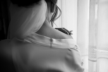 A woman in a dressing gown at the window. Girl's hand on her shoulder with a beautiful manicure