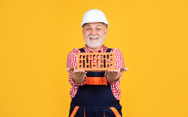cheerful senior man bricklayer in hard hat on yellow background - obrazy, fototapety, plakaty