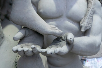 Kolkata, West Bengal, India - 7th October 2018 : Clay idol hands of Asura the demon, looking up for forgiveness from Goddess Durga by holding her feet , under preparation for "Durga Puja' festival.