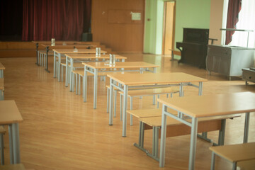 School canteen in Russia. Tables stand in row in hall. Place of public catering. Assembly hall in school.