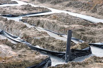 Concrete foundation footings insulated with foil against water and a plumbing installation