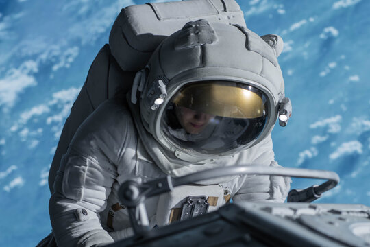 Female astronaut performing spacewalk, working on a outer part of a space craft