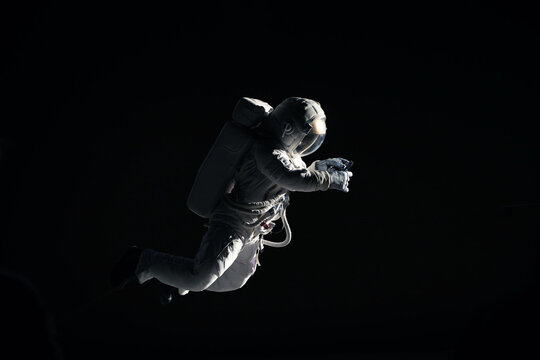 Caucasian female astronaut using her mobile phone during spacewalk, messaging, taking pictures