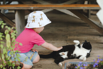 A little girl playing with funny cat outdoors. Child and her kitten outdoors