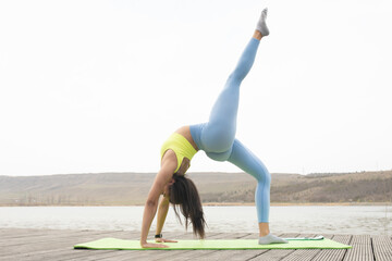 Healthy sports lifestyle. Athletic young black woman in sports dress doing fitness exercise on lake.