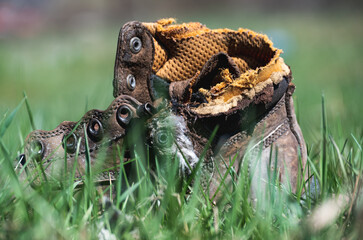 Boot, worn shoes thrown in nature. Broken boots thrown in the grass.