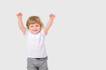 A small child holds his hands up and laughs. White background. Copy space . 