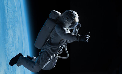 Female astronaut having a video call on her phone while performing spacewalk in open space, Earth in the background © supamotion