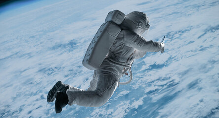 Female astronaut having a video call on her phone while performing spacewalk in space, Earth in the...