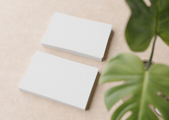 Blank white business cards with monstera plant on light brown background. Natural mockup for branding identity. Two cards to show both sides. Template for graphic designer. Free space. 3D rendering.