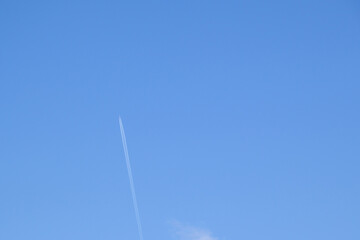 Trail of white smoke from the airplane on blue sky. Passenger plane in the sky, bottom view