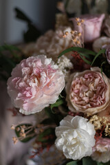 Vintage floral composition in glass vase on soft armchair. Bouquet of pink roses, peony flowers and eucalyptus.