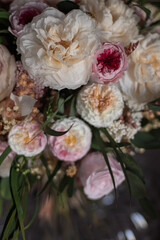 Vintage floral composition in glass vase on soft armchair. Bouquet of pink roses, peony flowers and eucalyptus.