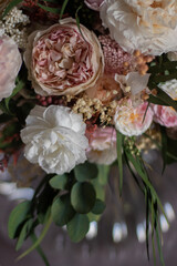 Vintage floral composition in glass vase on soft armchair. Bouquet of pink roses, peony flowers and eucalyptus.