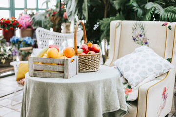 cozy veranda, table with basket of fruits and an armchair, greenhouse or a terrace for rest and relaxation, blooming garden