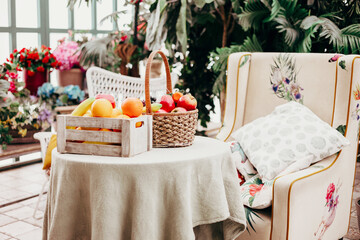 cozy veranda, table with basket of fruits and an armchair, greenhouse or a terrace for rest and relaxation, blooming garden