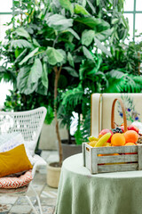 cozy veranda, table with basket of fruits and an armchair, greenhouse or a terrace for rest and relaxation, blooming garden