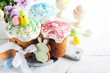 Traditional Easter sweet bread or cakes with white icing and sugar decor and quail eggs over white wooden table. Various Spring Easter cakes. Happy Easter day. Christian traditions. Top view.