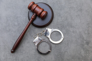 Law theme. Court of law trial in session. Judge gavel handcuffs on grey table in lawyer office or court session. Mallet of judge on concrete stone grey background. Justice human rights concept.