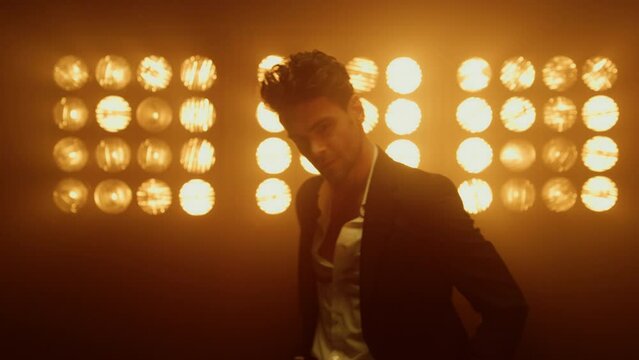 Closeup man model moving on stage night club. Sexy guy posing in spotlights.