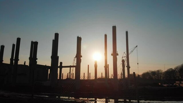 Sunset view landscape at construction site. New factory building cement poles, heavy machinery and workers. Scenery. Aerial shot.