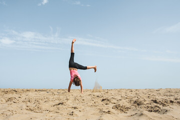 Girl doing a cartwheel in the sand on the beach