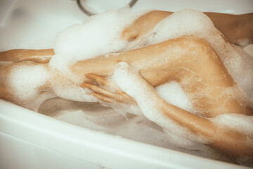 Fototapeta premium Women's feet in bath foam. View from above. Enjoy and relax in a spa hotel