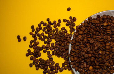 Coffee beans isolated on the yellow background. Joyful minimal coffee-theme with copy space
