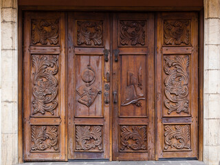 Horizontal view of old wooden door with carved floral motifs and books, globe and old fashioned feather writing pen, Quito, Ecuador