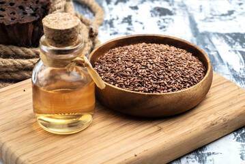 flaxseeds in a wooden bowl and a bottle of linseed oil