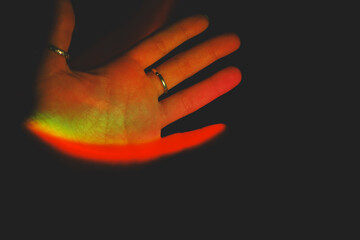 Detail of human hands illuminated by colorful lights
