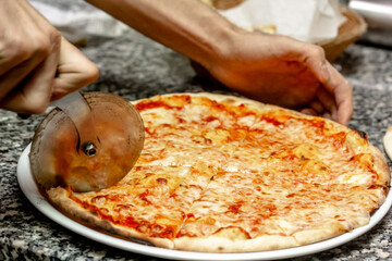 The chef cuts the pizza with a special round knife
