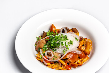 Pickled forest mushrooms with onions and parsley are on a plate