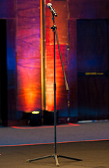 Microphone with pedestal on stage with colorful and illuminated background