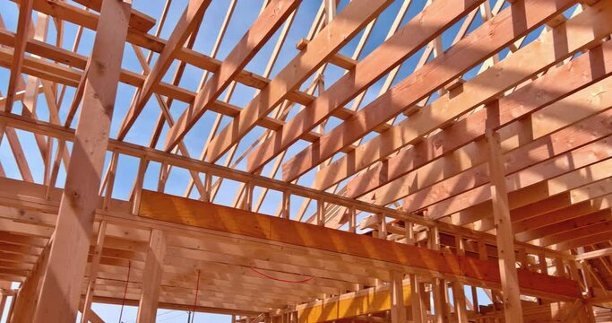 Construction team, new building construction with roof carpentry works on roof at height workers nailing wood beams the roof